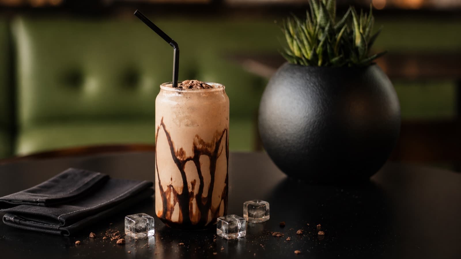 Chocolate shake with chocolate drizzle beside a plant pot